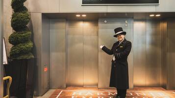 Un ascensor con un cartel que dice "HARMONIE EMBRASEe OSAKA" y una persona con uniforme dentro.
