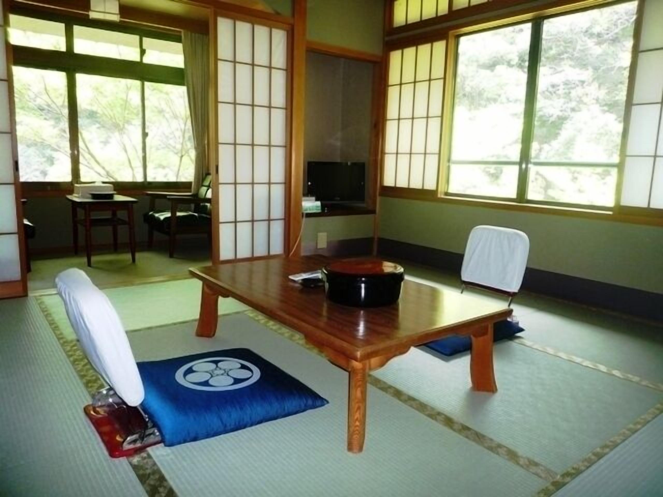 Um quarto japonês tradicional, com tatames, uma mesa de madeira baixa e um painel shoji.