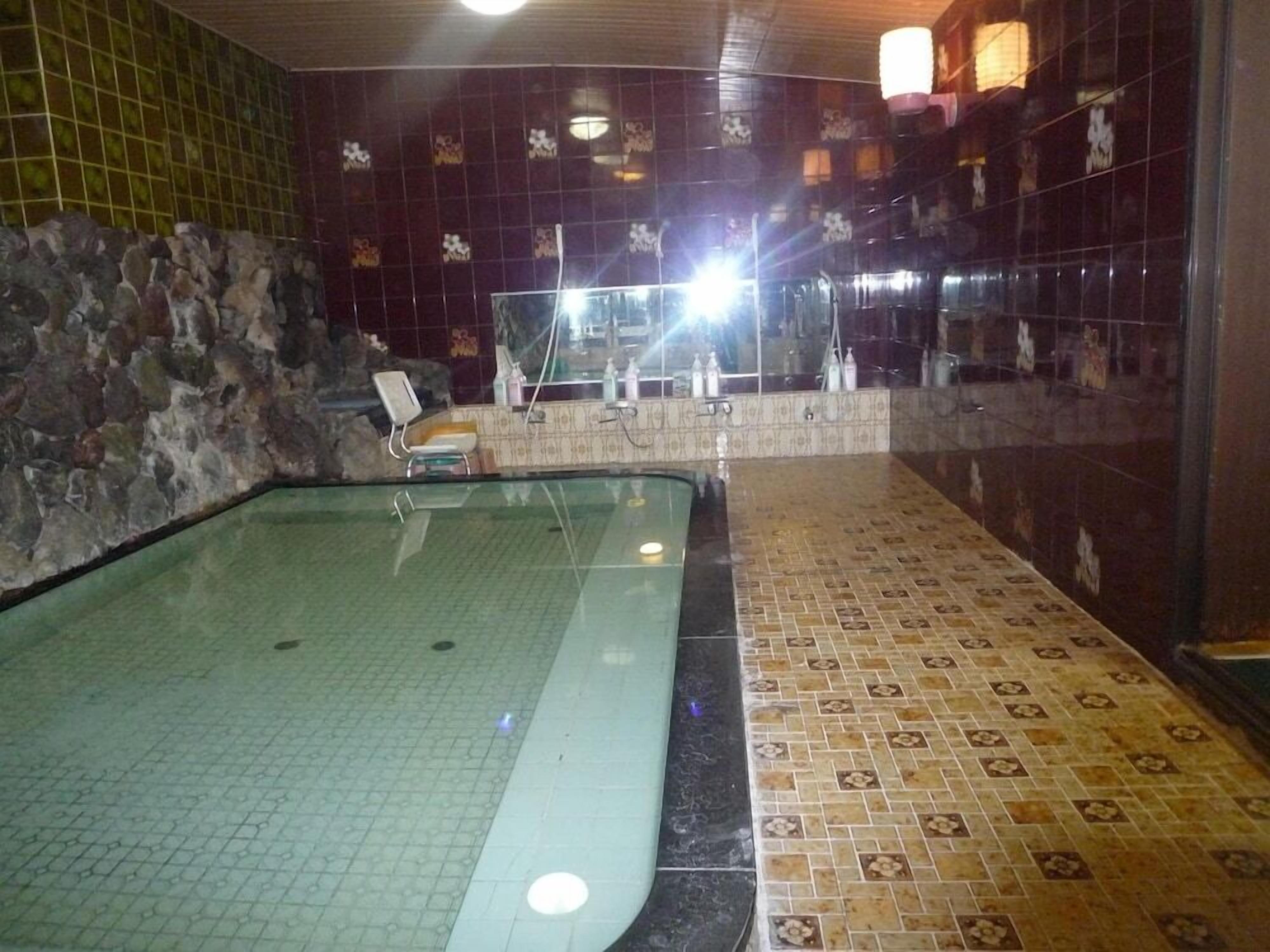 Un'area benessere con pavimento piastrellato, parete in pietra e piscina vetrata.