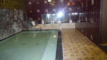 Un'area benessere con pavimento piastrellato, parete in pietra e piscina vetrata.