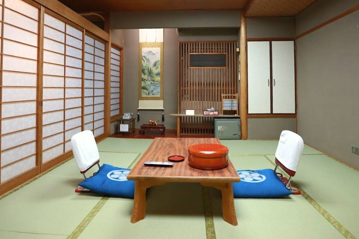 Una habitación japonesa tradicional con suelo de tatami, una mesa de madera baja y puertas correderas shoji.