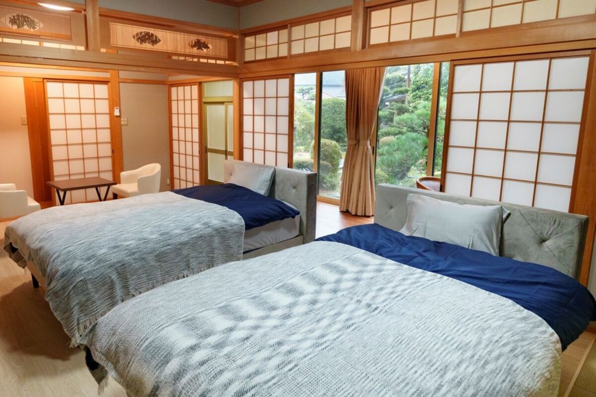 A traditional Japanese-style bedroom with two beds, a small table, and sliding doors.