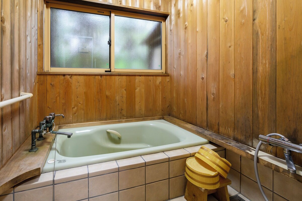 Baño de cabaña de madera con bañera, ventana y retrete de madera.