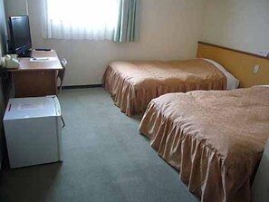 A hotel room with two beds, a desk, and a small refrigerator. - Yuin Ueda (Ueda)