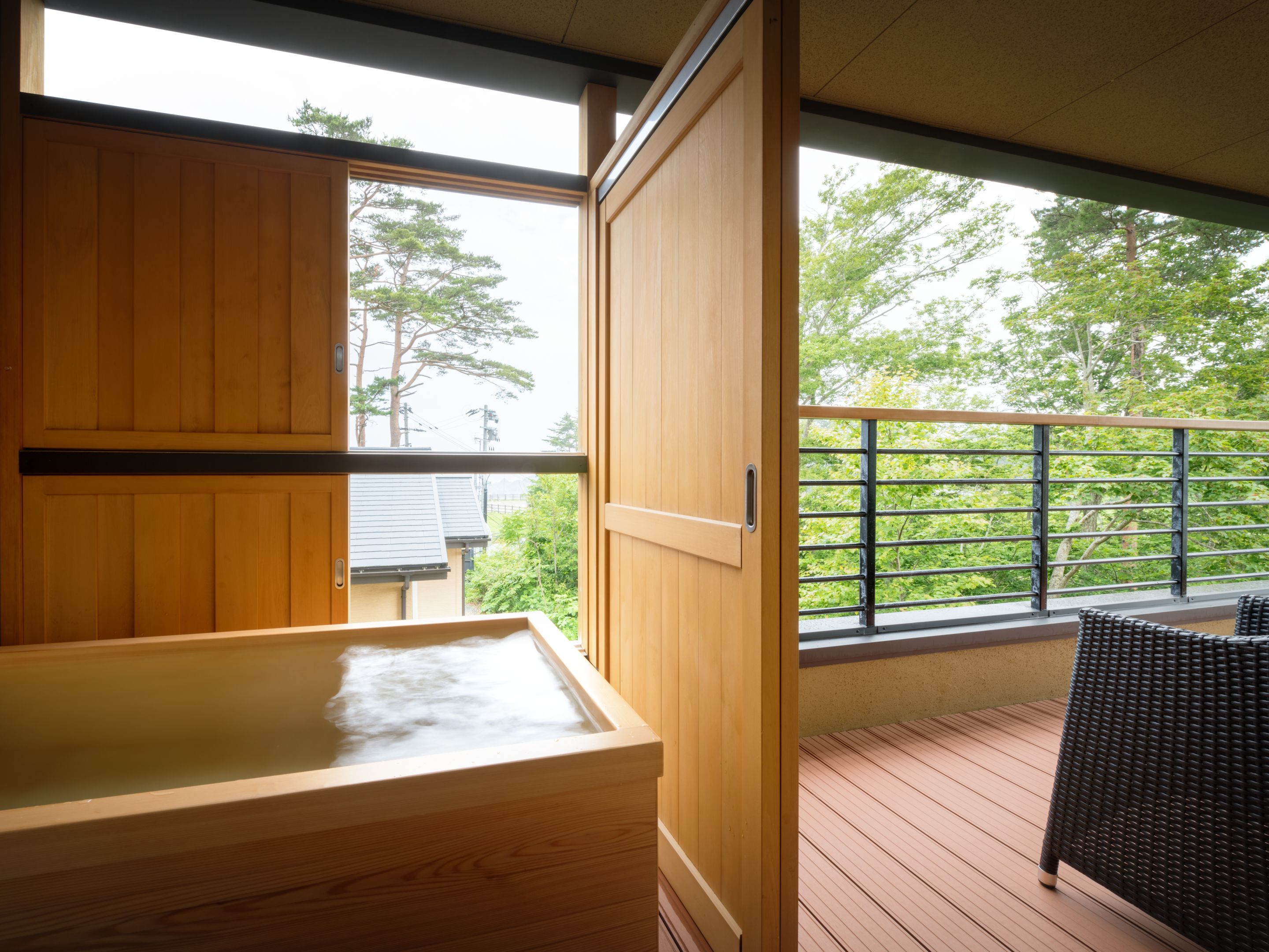 Eine Holzsauna mit Blick auf einen Balkon und Bäume.