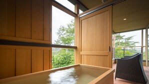 Una bañera de hidromasaje de madera con vistas a la vegetación.