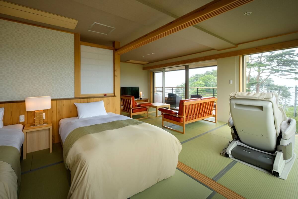 A hotel room with a bed, a desk, a chair, and a massage chair.