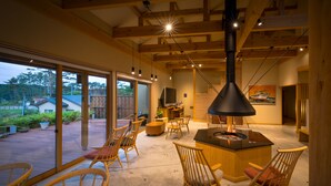 Amplia sala de estar con una chimenea grande, muebles de madera y vistas al exterior.