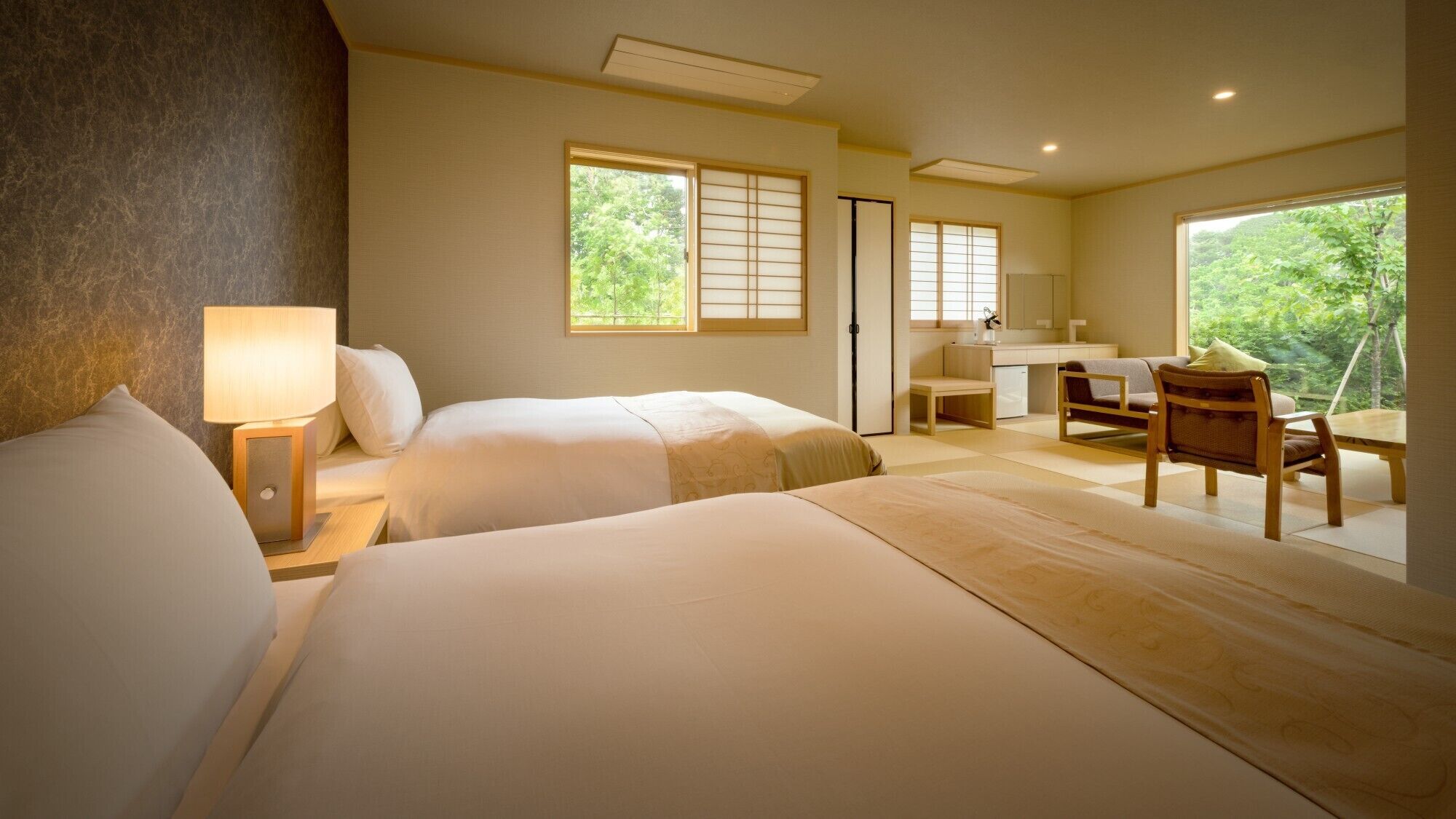 Une chambre d’hôtel avec deux lits, un bureau, une chaise et une vue sur la verdure.