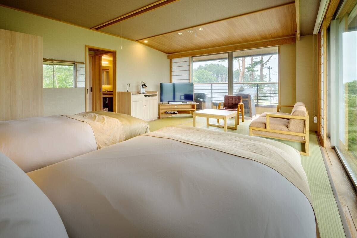 A hotel room with two beds, a TV, a desk, and a chair.