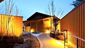 Un sendero que conduce a un edificio con un acceso cubierto y una cerca de madera a un lado.