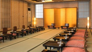 A traditional Japanese-style room with tatami mats, low tables, and red cushions. - Kusano Inn Kitakami (Kitakami)