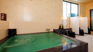 A spa area with a large rectangular pool, a small seating area, and a window providing natural light. - Kusano Inn Kitakami (Kitakami)
