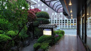 A traditional Japanese garden with a stone lantern, a wooden bridge, and a signboard. - Kusano Inn Kitakami (Kitakami)