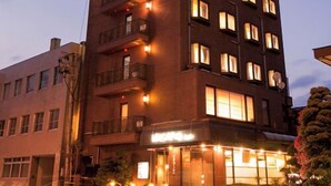 A multi-story hotel with a modern design, featuring balconies on the upper floors and a ground-level entrance with a sign. - Kusano Inn Kitakami (Kitakami)
