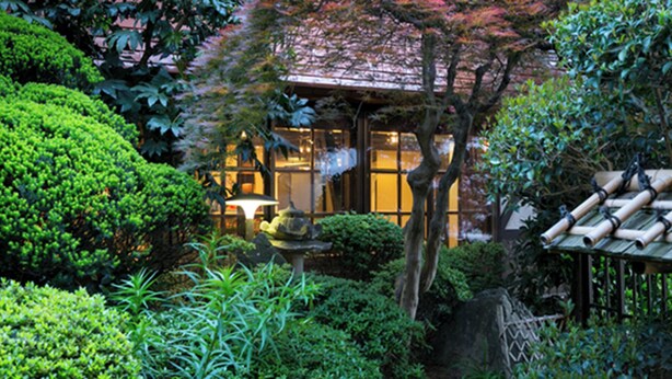 A traditional Japanese garden with a stone lantern, bamboo structures, and lush greenery. - Kusano Inn Kitakami (Kitakami)
