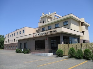 A hotel with a modern architectural design, featuring a prominent entrance with a covered area and a parking lot in front.