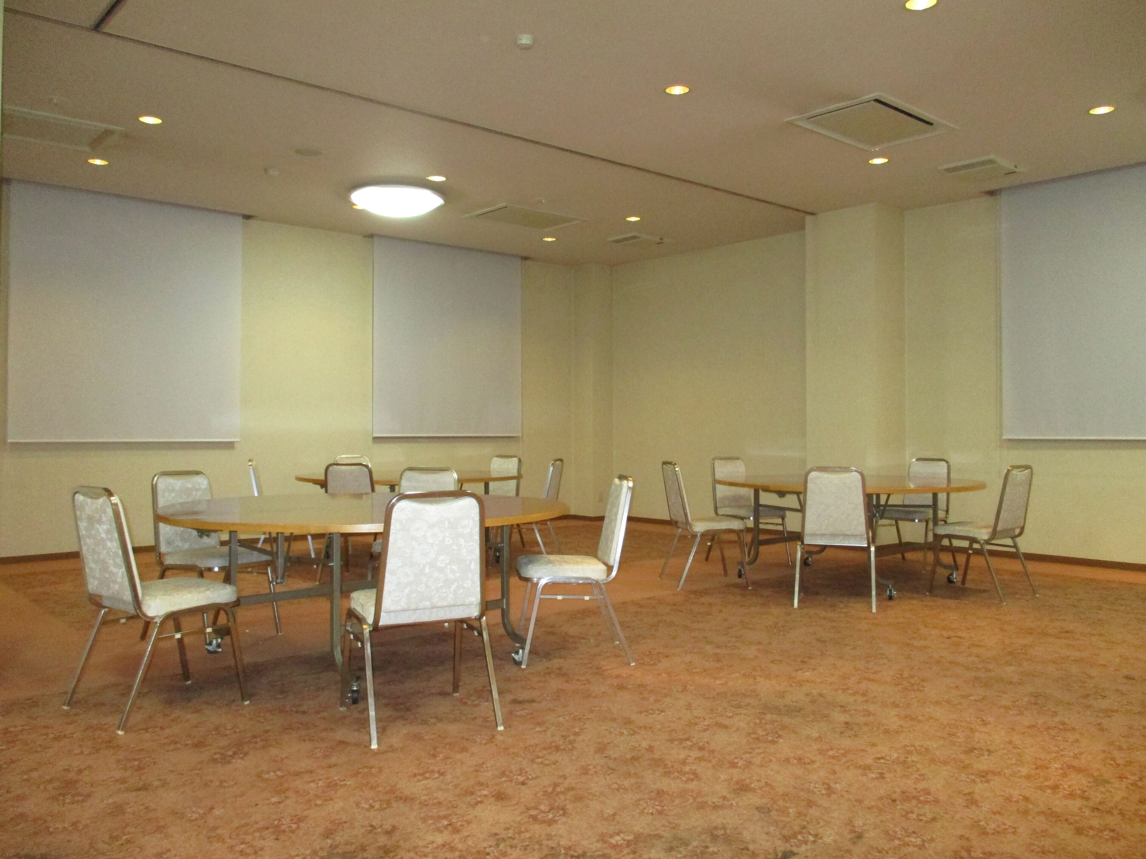 A conference room with a carpeted floor, multiple tables, and chairs.