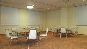 A conference room with a carpeted floor, multiple tables, and chairs.
