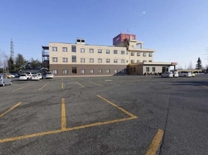 A multi-story building with a parking lot in front. - Otofuke (Otofuke)