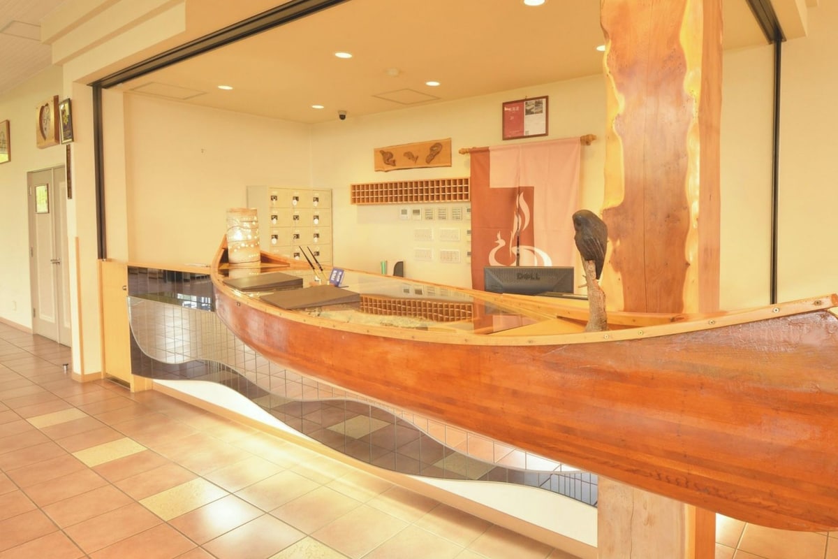 A reception desk with a wooden boat design, a fire extinguisher, and a wall-mounted display.