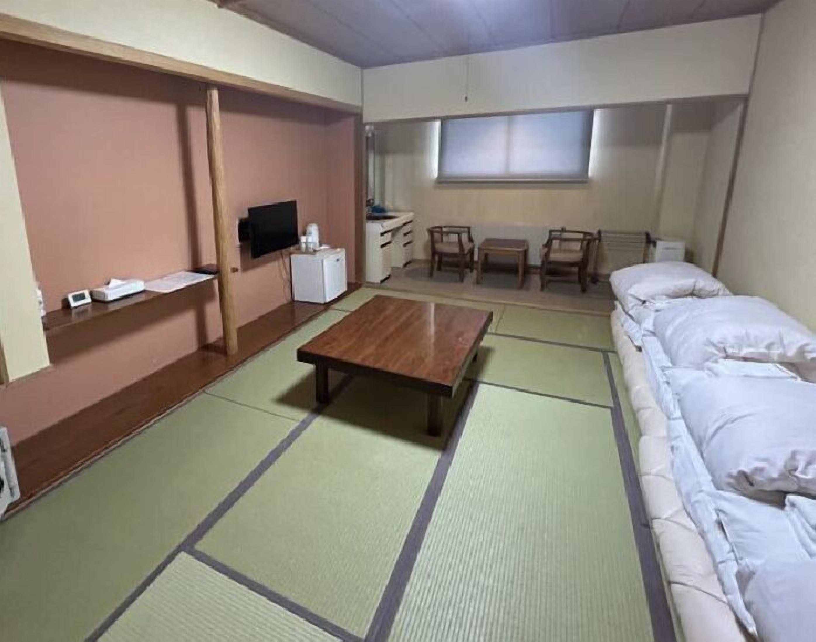 Una habitació amb esteves de tatami, un llit, una televisió, una taula petita i una finestra.