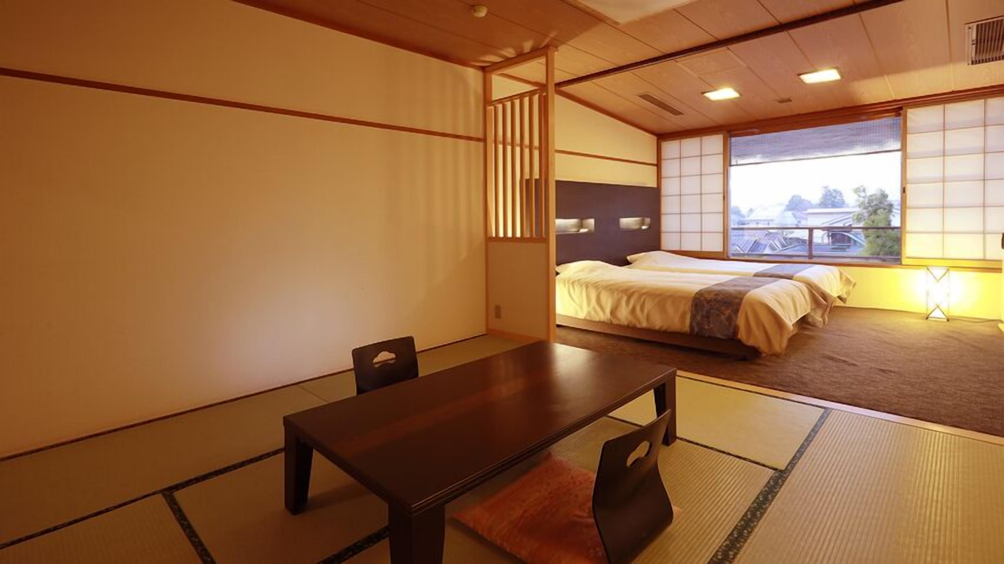 Une pièce de style japonais traditionnel, avec un sol recouvert de tatamis, une table basse et un lit équipé d’un futon.