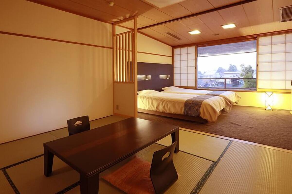 Une pièce de style japonais traditionnel, avec un sol recouvert de tatamis, une table basse et un lit équipé d’un futon.