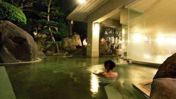 A person in a pool with rocks and trees in the background. - Isawa Onsenkyo Ryokan Kisen (Fuefuki)