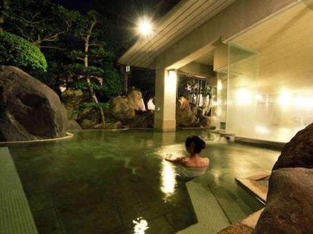 A person in a pool with rocks and trees in the background.