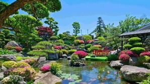 A serene garden with a pond, koi fish, and a red bridge. - Isawa Onsenkyo Ryokan Kisen (Fuefuki)