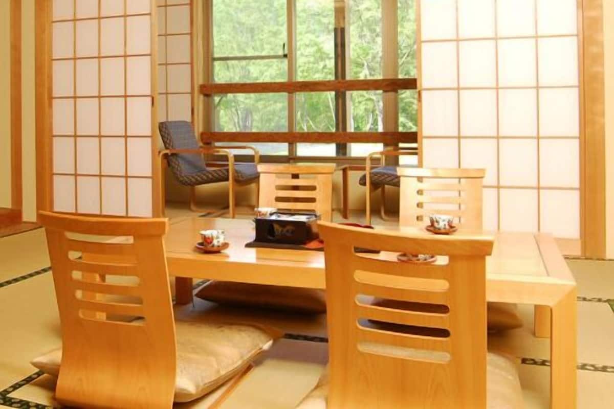 A traditional Japanese-style room with tatami flooring, a low table, and wooden chairs.