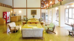 A spacious lobby with wooden beams, a reception desk, seating area, and a Coca-Cola refrigerator. - Azuki Onsen Kaboku no Yado (Minamiaizu)
