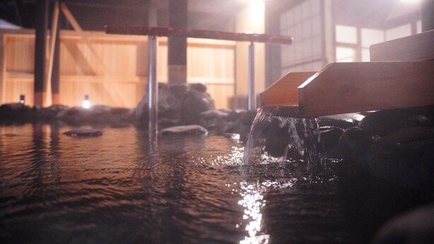 A water feature with a wooden structure, a stone base, and a metal railing. - Azuki Onsen Kaboku no Yado (Minamiaizu)