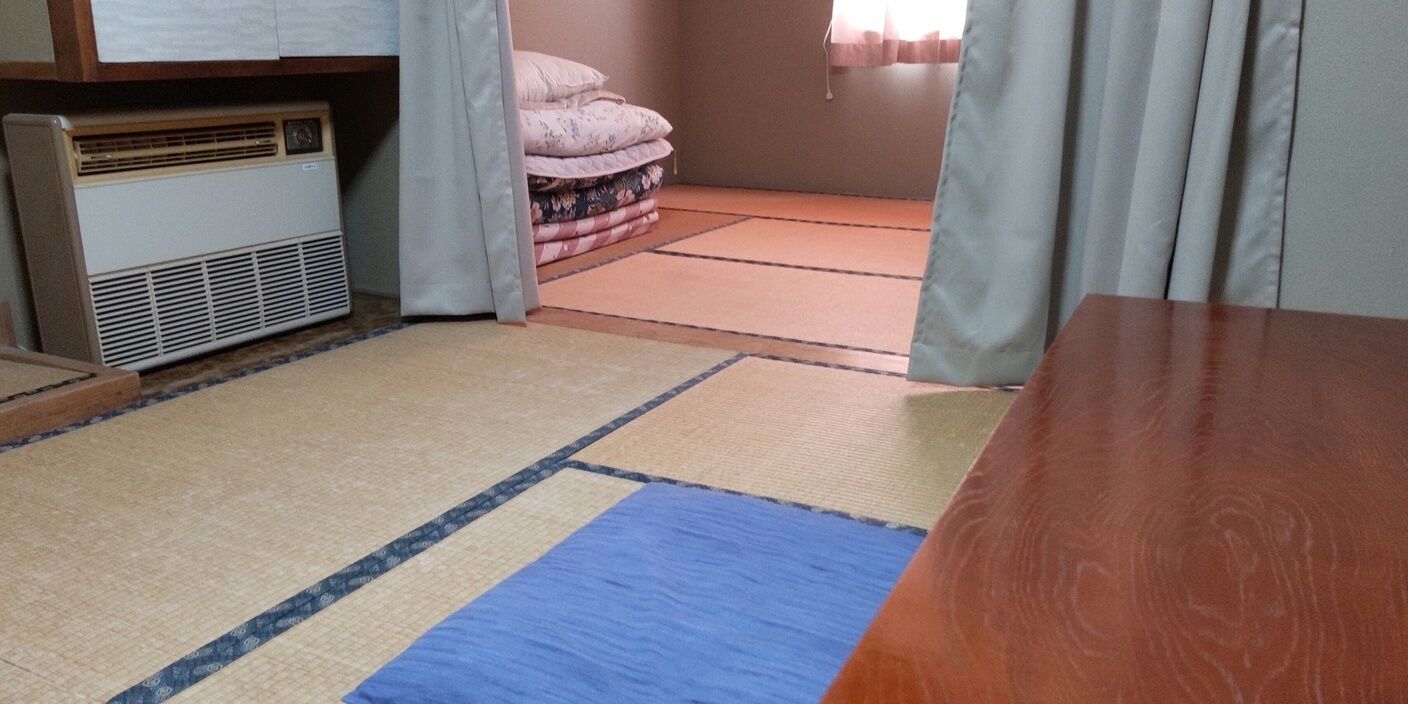Een kamer met tatami matten, een verwarming en een bed met kussens.