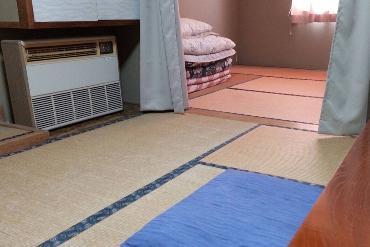 A room with tatami mats, a heater, and a bed with pillows.