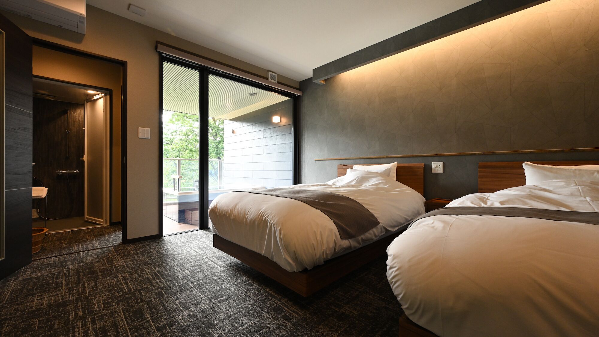 Ein Hotelzimmer mit Bett, Badezimmer und einer Schiebetür zum Außenbereich.