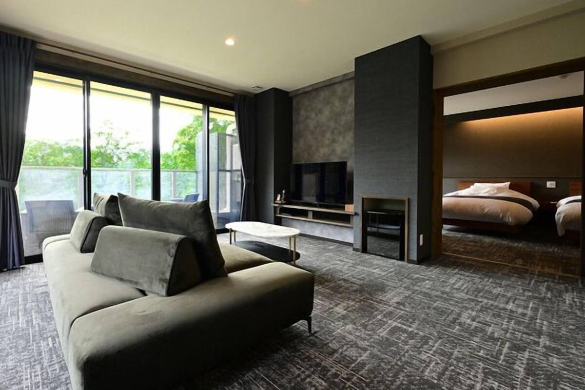 Ein modernes Hotelzimmer mit Sofa, Fernseher, Kamin und Balkonblick.