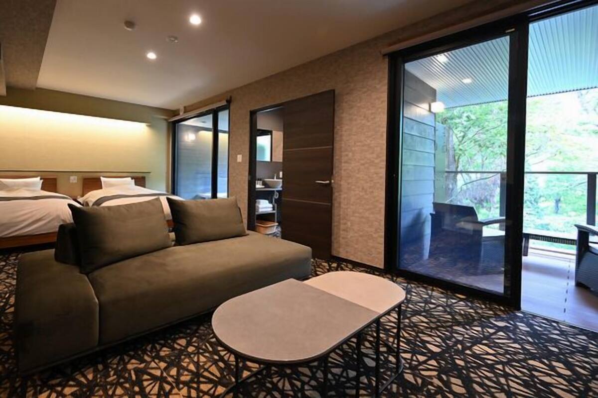 Ein Hotelzimmer mit einer Couch, einem Bett, einem kleinen Tisch und einem Balkon mit Blick.