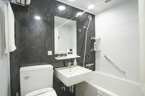 A modern bathroom with a black marble wall, a white sink, a toilet, and a bathtub. - Quintessa Hotel Tokyo Haneda Comic & Books (Tokyo)