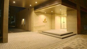 A hotel entrance with a modern design, featuring a prominent logo on the wall and a glass door leading inside. - Quintessa Hotel Tokyo Haneda Comic & Books (Tokyo)