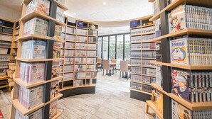 A bookstore with curved shelving and a central seating area. - Quintessa Hotel Tokyo Haneda Comic & Books (Tokyo)