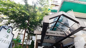 Una entrada de hotel moderna con fachada de vidrio y señalización que dice 'Mikasa City Hotel'.