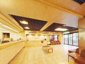 A reception area with a counter, seating, and a view through the window. - Mitaka City Hotel (Mitaka)