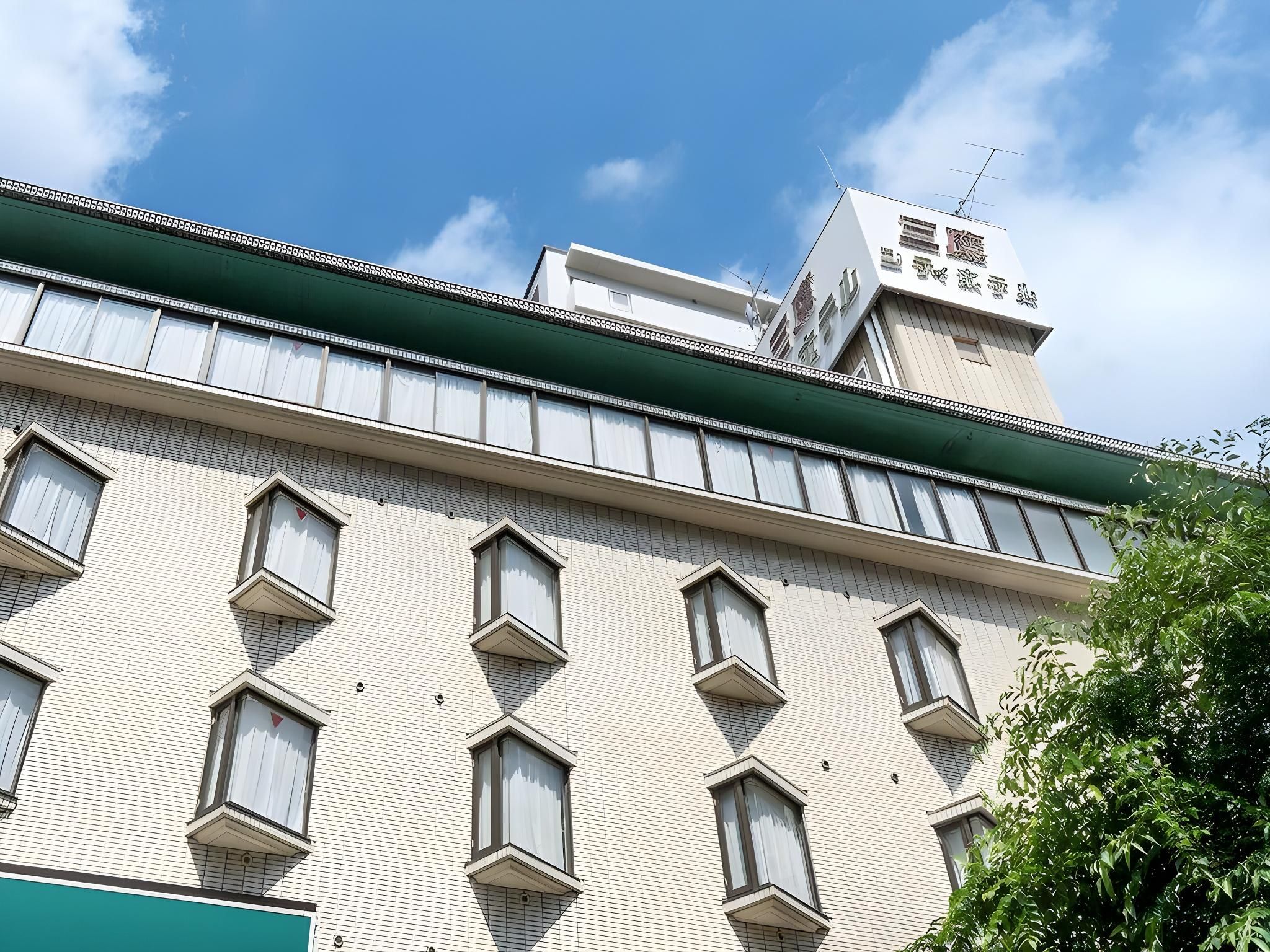 A multi-story building with a flat facade, multiple windows, and a green awning.
