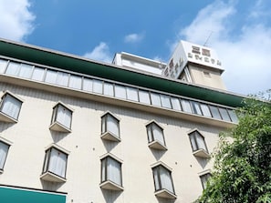 A multi-story building with a flat facade, multiple windows, and a green awning.