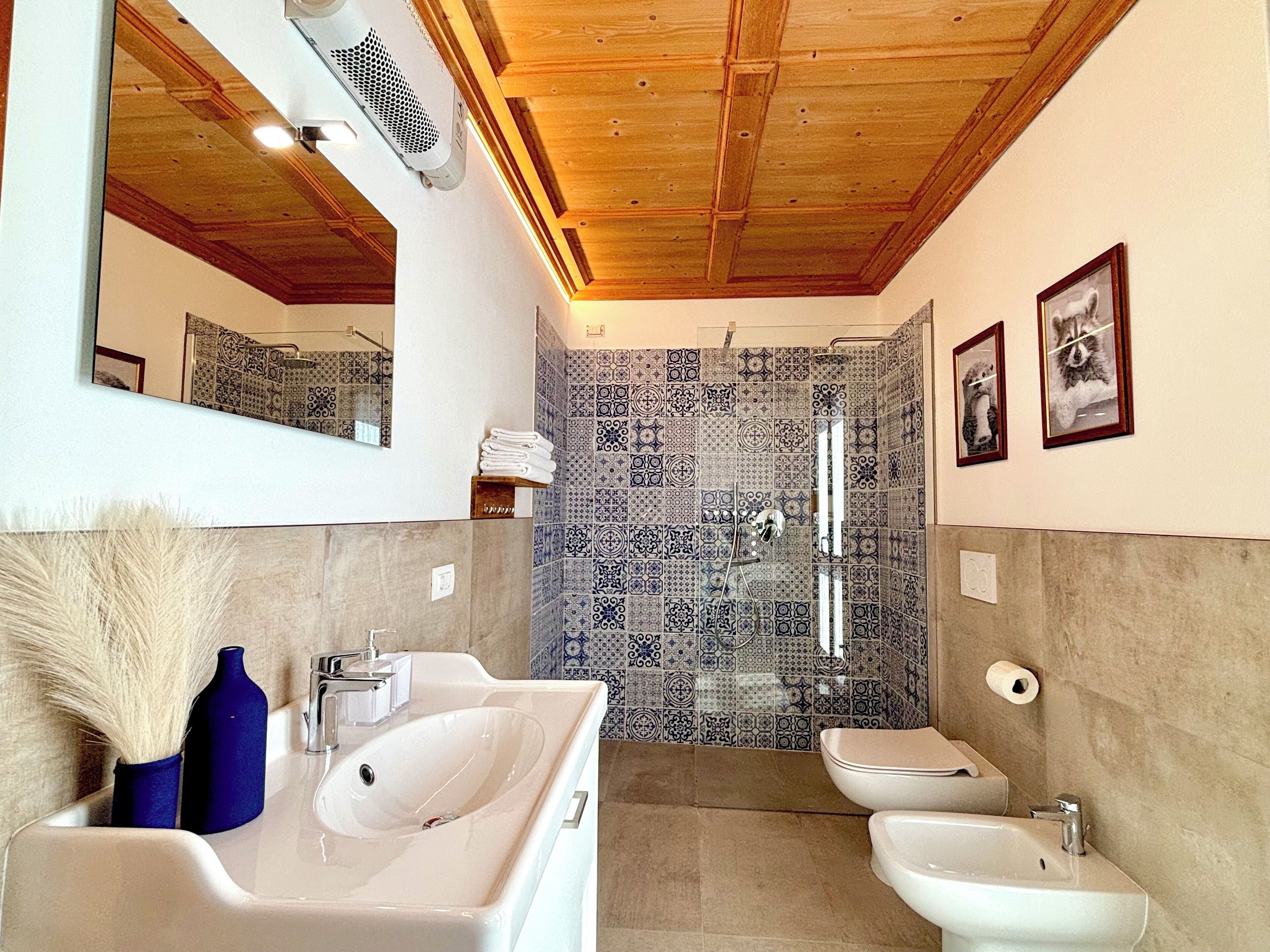Une salle de bain avec un grand miroir, deux lavabos, une douche et des carreaux décorés.