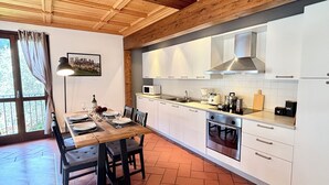 A modern kitchen with white cabinets, a stainless steel range hood, and a tiled backsplash.