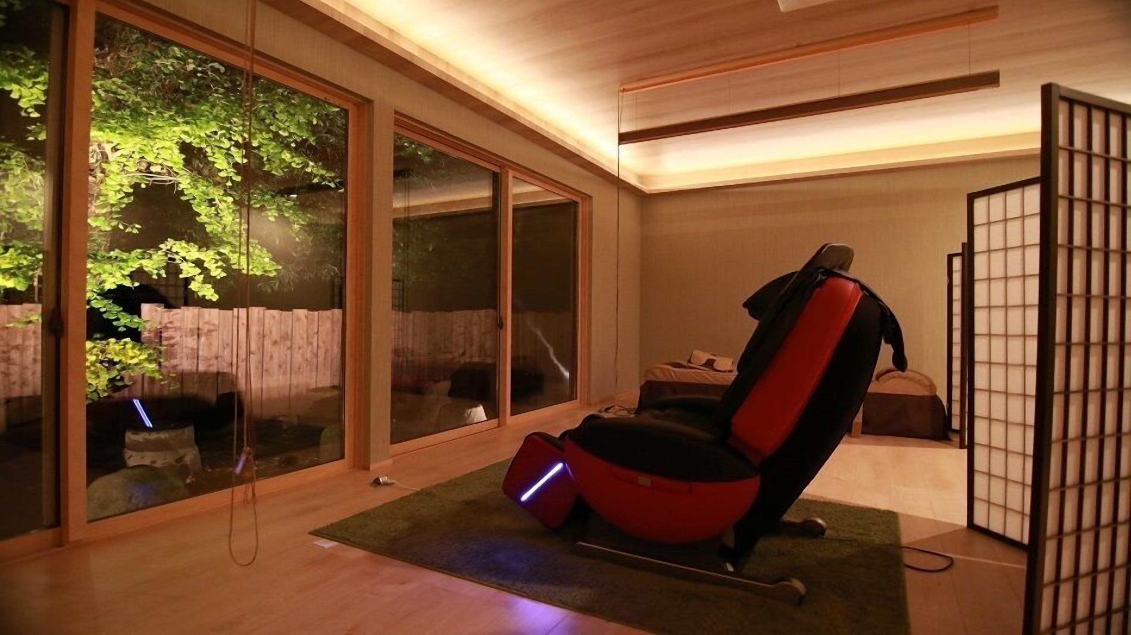 A modern room with sliding glass doors, a massage chair, and a partition with a grid design.