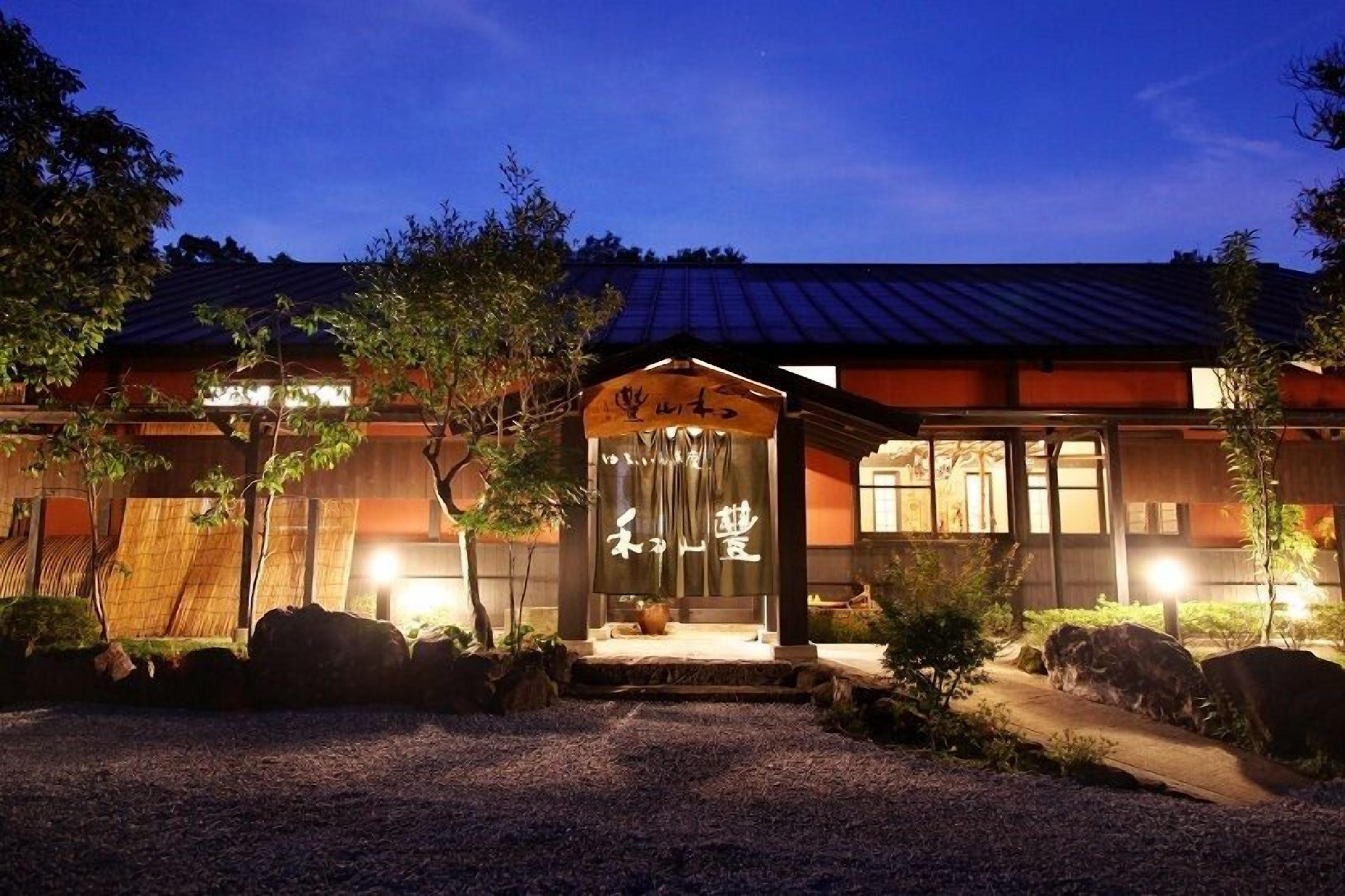 A traditional Japanese building with a covered entrance, wooden flooring, and a gravel pathway leading to the door.